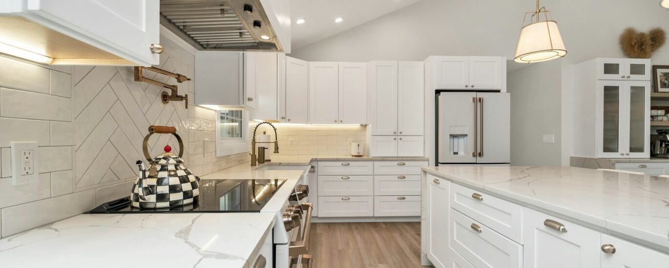 a kitchen with white cabinets and marble counter tops
