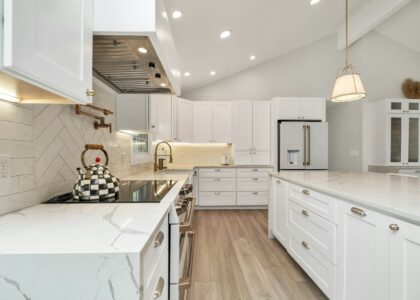 a kitchen with white cabinets and marble counter tops